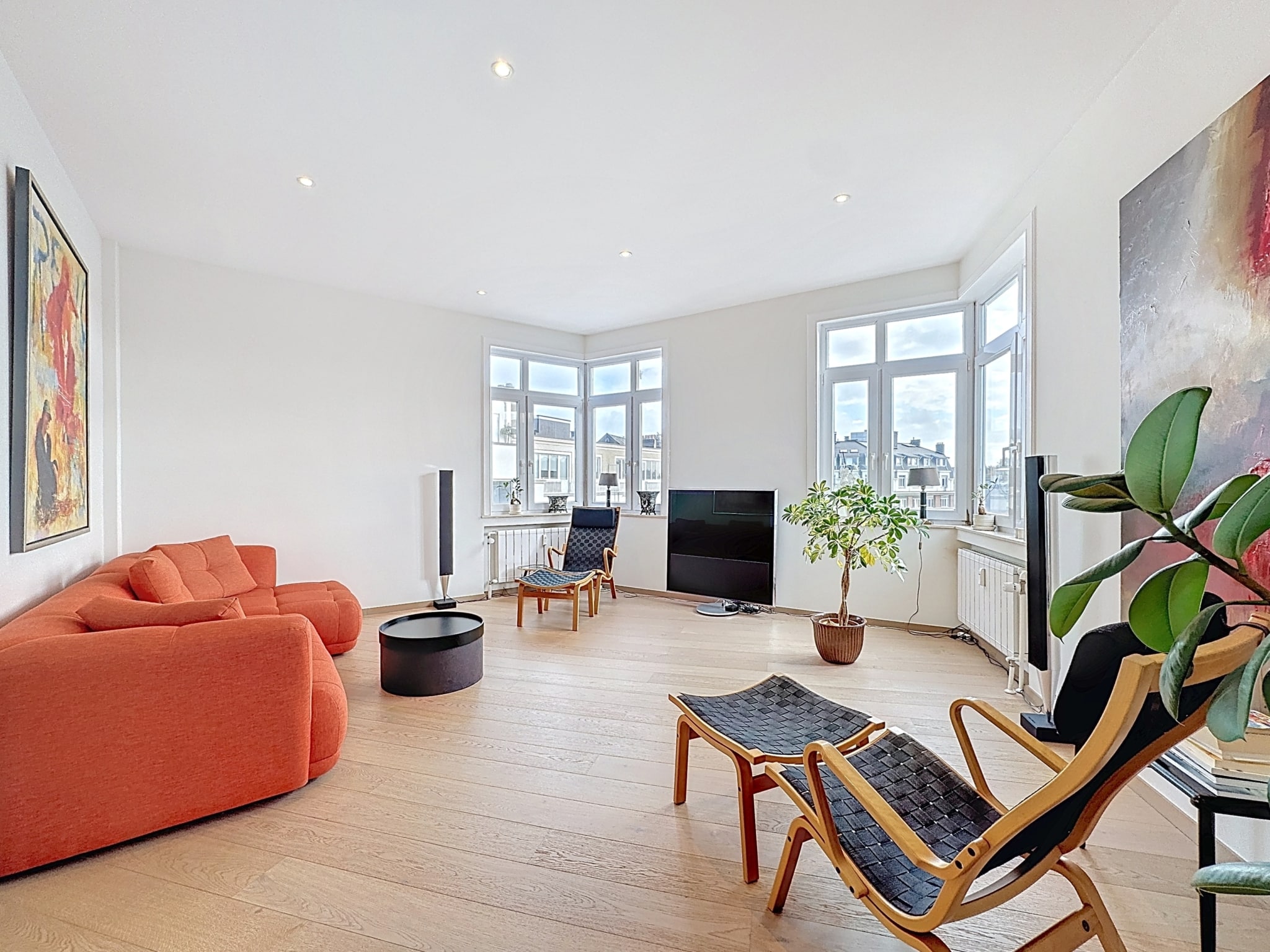 Lichte moderne woonkamer in Lejeune - You Real Estate Agency Lichte moderne woonkamer in Lejeune met oranje bank en grote ramen