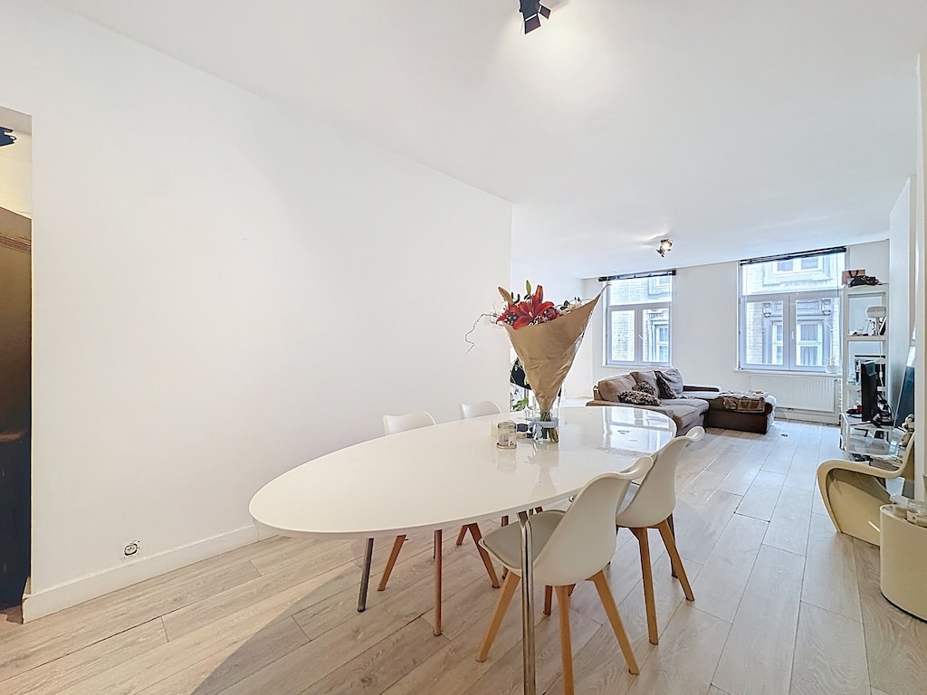 Salon lumineux moderne avec salle à manger, canapé cosy et grandes fenêtres à Saint-Gilles.