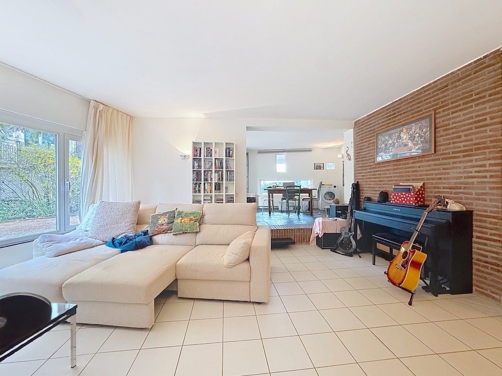 Lichte woonkamer met bank, muziekinstrumenten en open ruimte in Antibes.