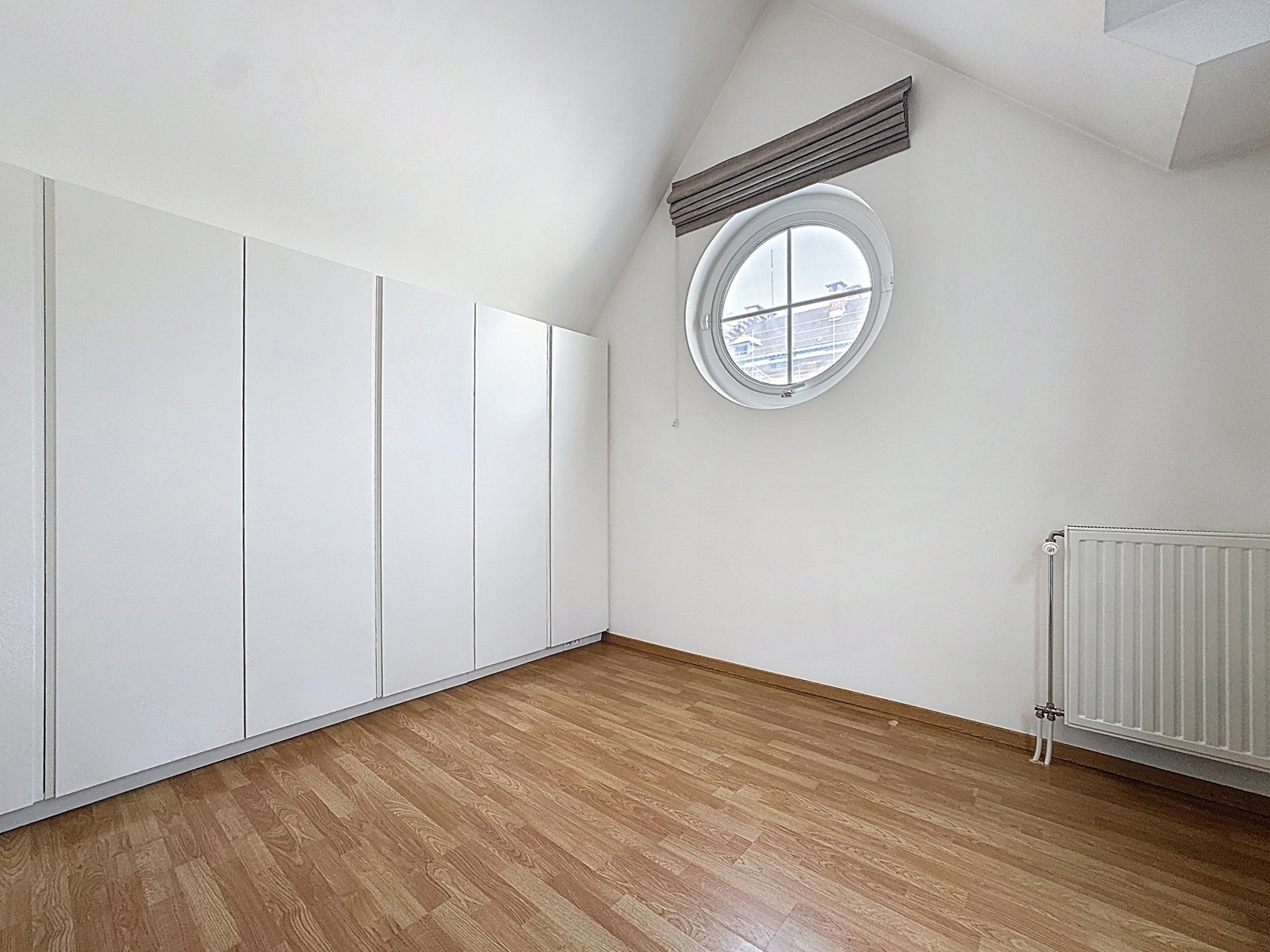 Chambre Mansardée avec Fenêtre Ronde – You Real Estate Agency Chambre mansardée moderne avec parquet, rangements intégrés et fenêtre ronde