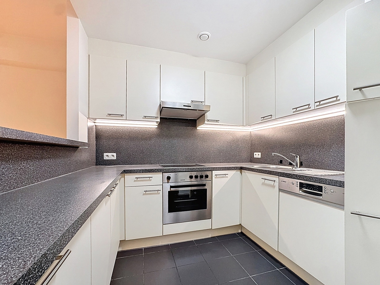 Cuisine Moderne Blanche en U – You Real Estate Agency Cuisine moderne blanche en U avec plans gris, four encastré et hotte inox