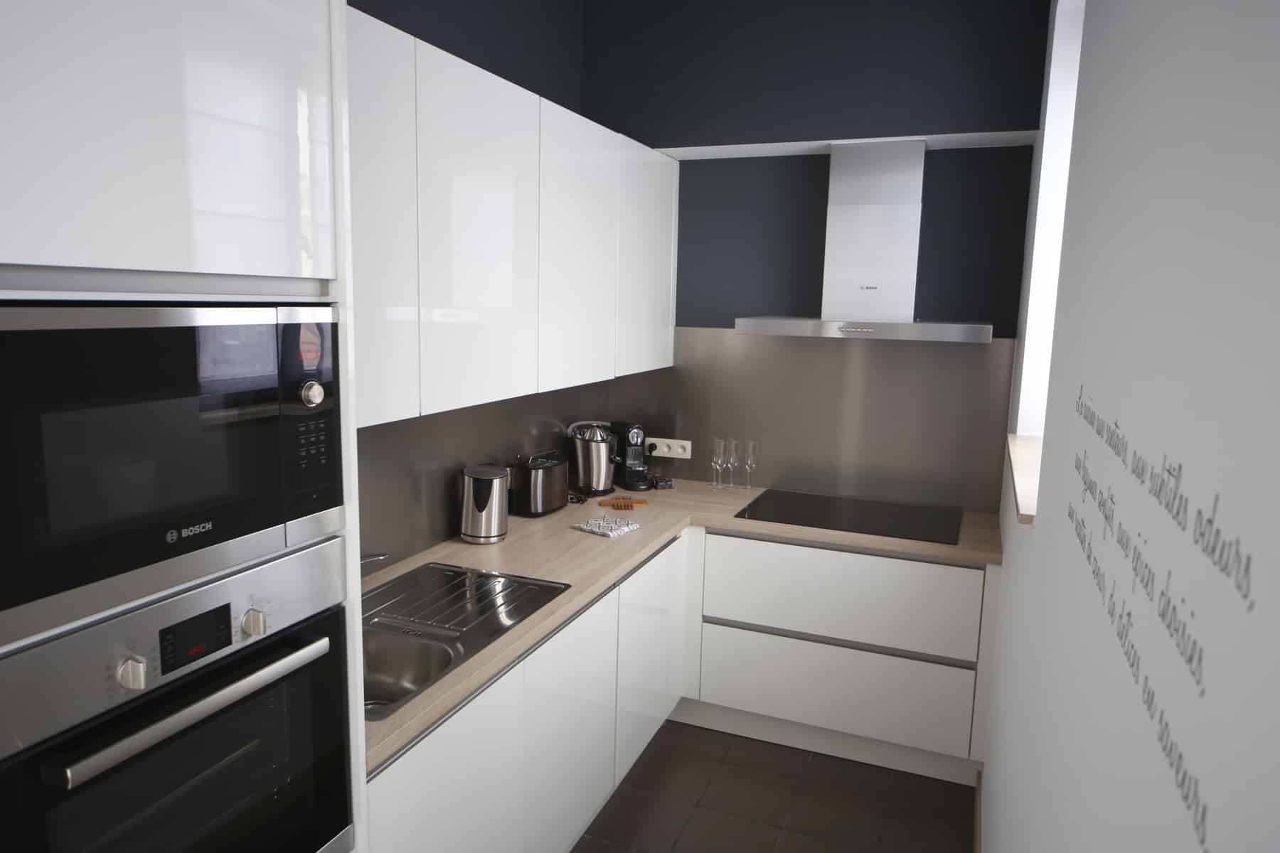 Cuisine Équipée Blanche et Inox – You Real Estate Agency Cuisine équipée moderne blanche avec électroménager inox, plan bois et crédence gris foncé