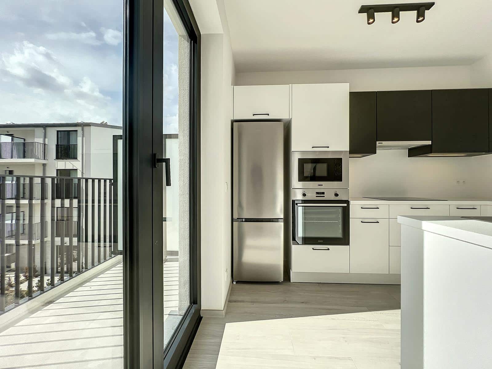 Cuisine Lumineuse avec Balcon – You Real Estate Agency Cuisine contemporaine lumineuse avec balcon, réfrigérateur inox et vue urbaine