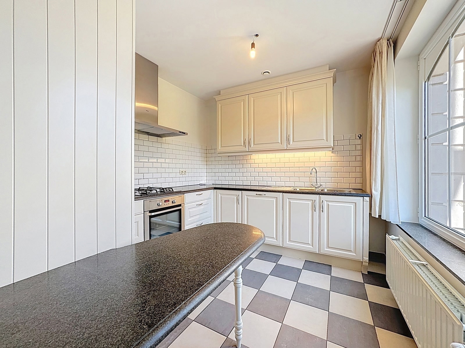 Bright kitchen with Damier floor - You Real Estate Agency Bright kitchen with white furniture, dark worktops and black-and-white checkerboard flooring