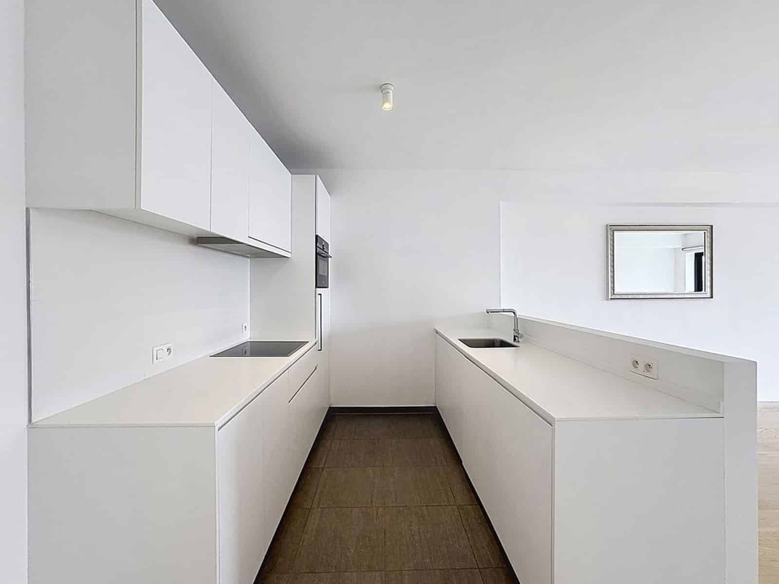 Cuisine Blanche Moderne - You Real Estate Agency Modern white minimalist kitchen with sink, integrated hob and dark tiled floor