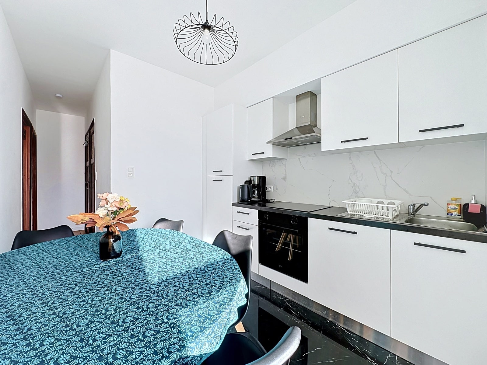 Cuisine Moderne avec Coin Repas – You Real Estate Agency Cuisine moderne équipée avec coin repas, meubles blancs et plan de travail noir