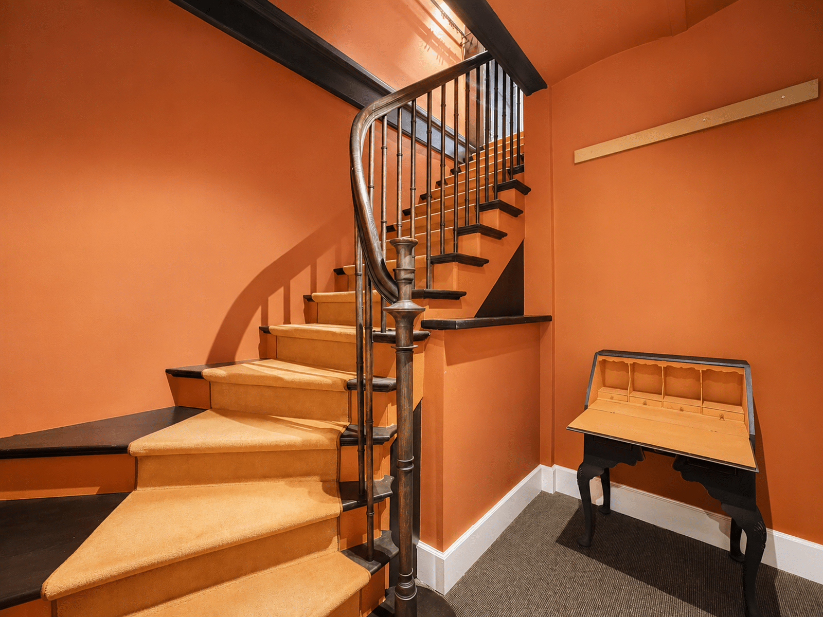 Warm staircase with Orange Walls - You Real Estate Agency Interior terracotta staircase with dark wood banister and beige carpeting