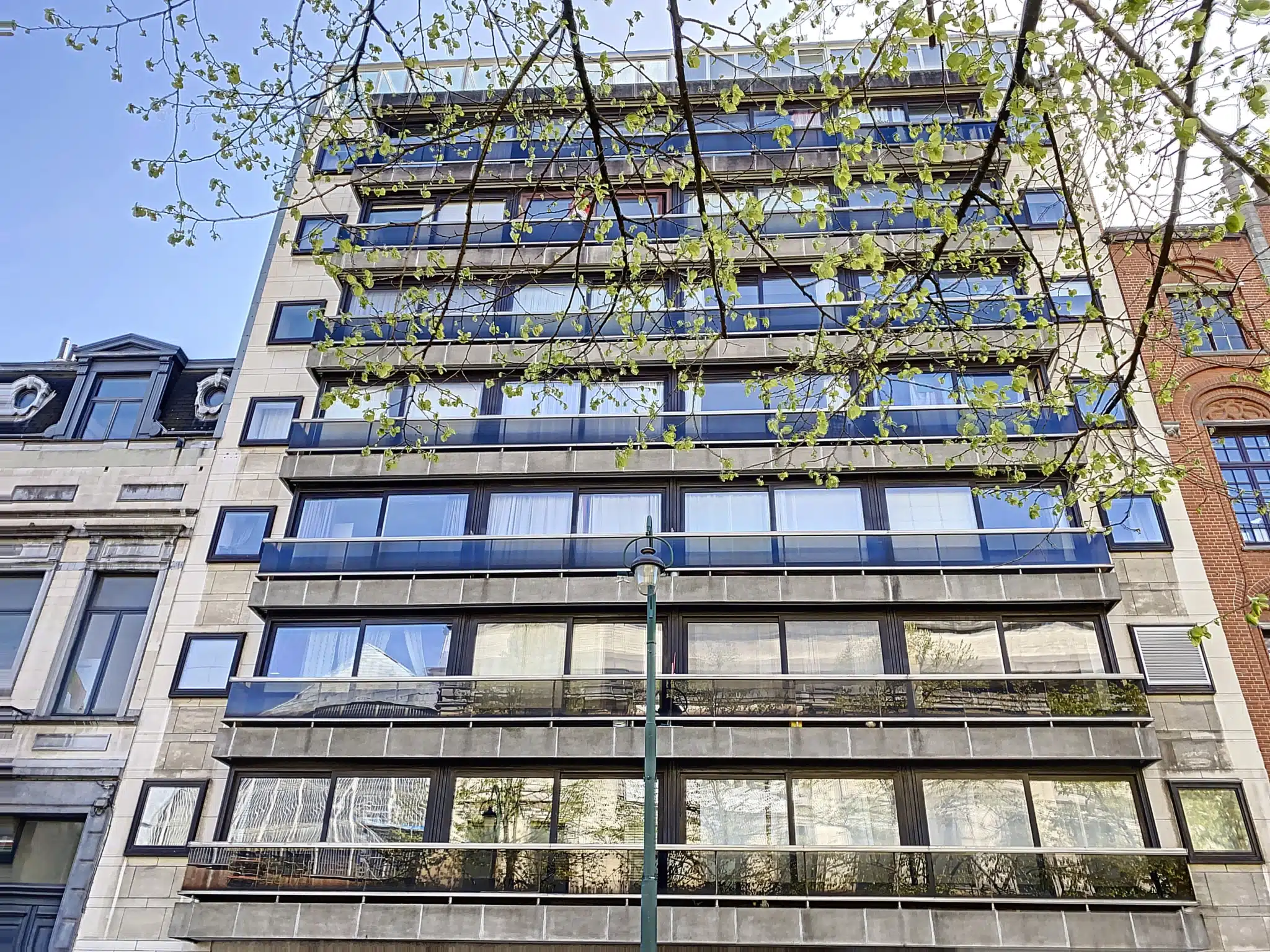 Modern building facade - You Real Estate Agency Modern building facade with glazed apartments and balconies in the city center.