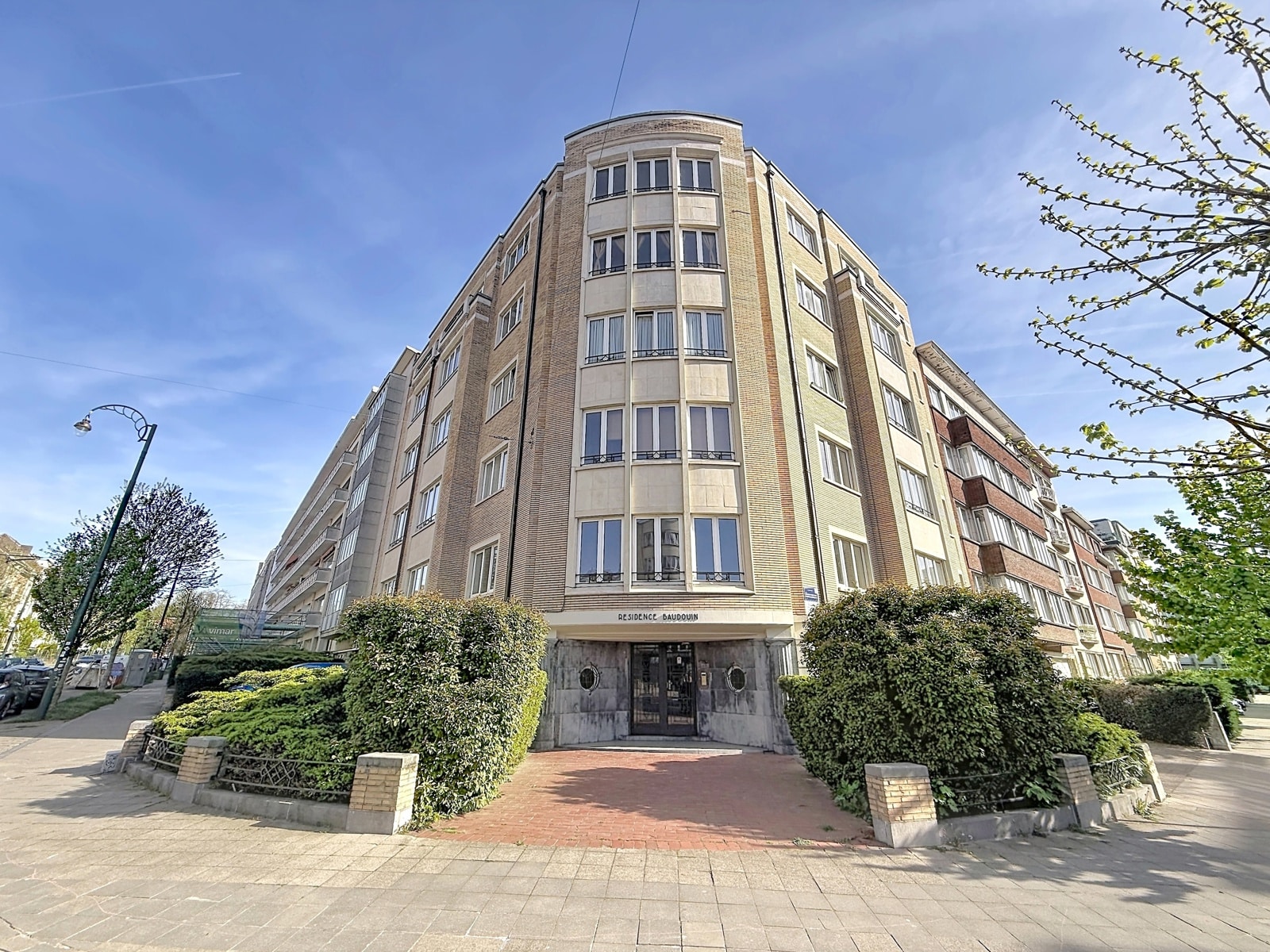 Façade of the Résidence Baudouin - You Real Estate Agency Façade of the Résidence Baudouin, an elegant residential building with landscaped entrance