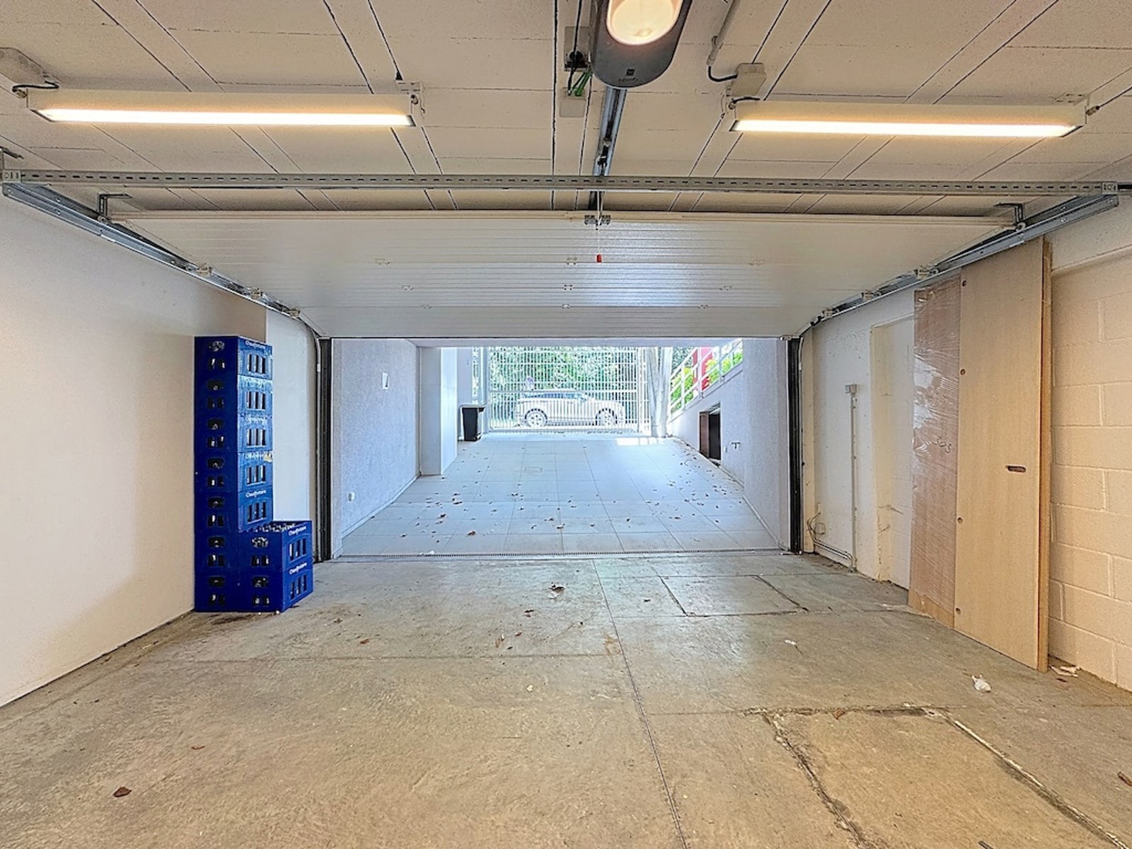 Garage Couvert avec Porte Motorisée – You Real Estate Agency Garage couvert spacieux avec porte motorisée, rangements et accès extérieur sécurisé