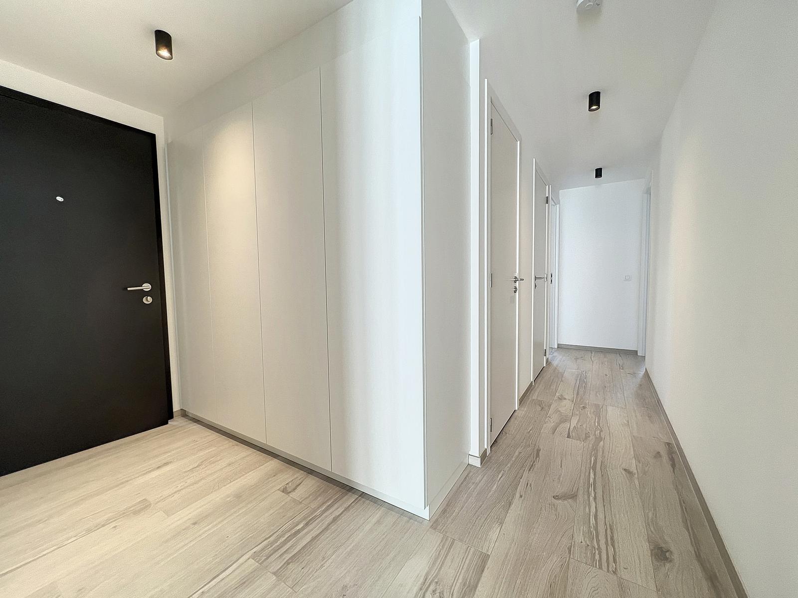 Hall d’Entrée Moderne avec Rangements – You Real Estate Agency Hall d’entrée moderne lumineux avec porte noire, rangements intégrés et sol bois clair