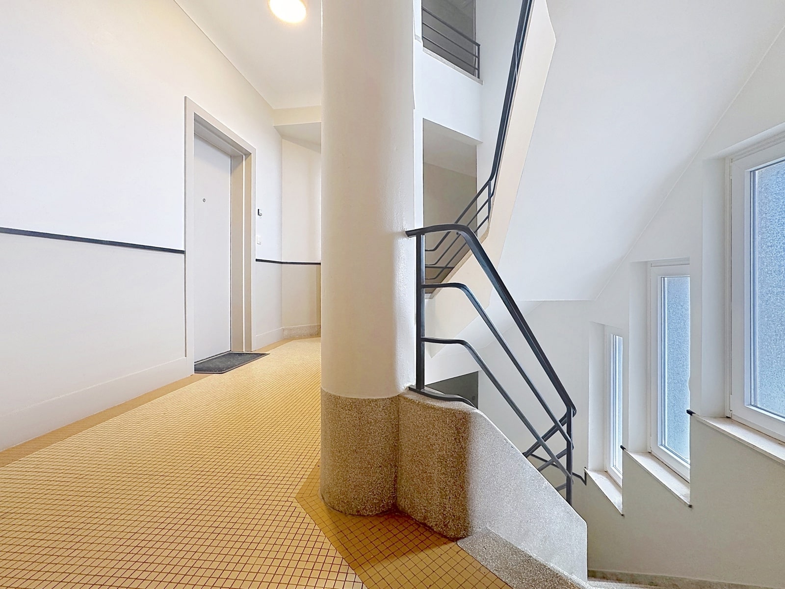 Luminous Stair Hall with Column - You Real Estate Agency Bright modern staircase hall with terrazzo column and black metal banisters