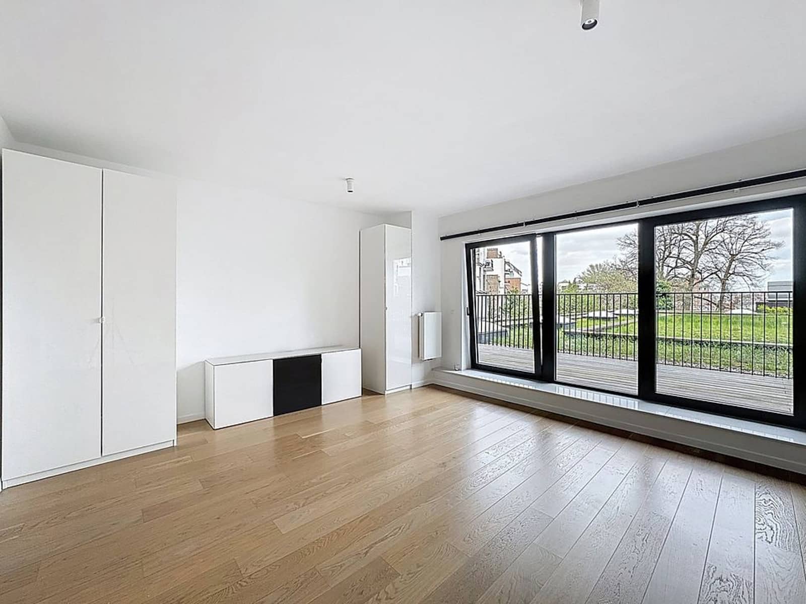 Bright living room with balcony - You Real Estate Agency Bright modern living room with light parquet flooring, bay window and balcony overlooking greenery