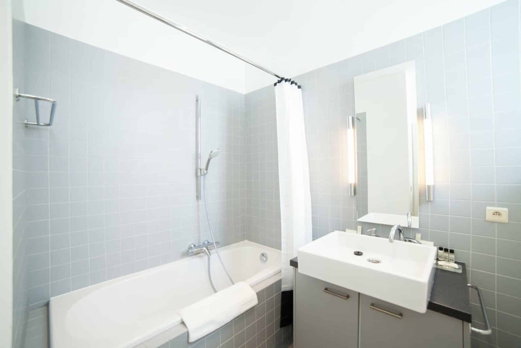 Salle de Bain Carrelée avec Baignoire – You Real Estate Agency Salle de bain moderne carrelée avec baignoire, douche et meuble vasque gris