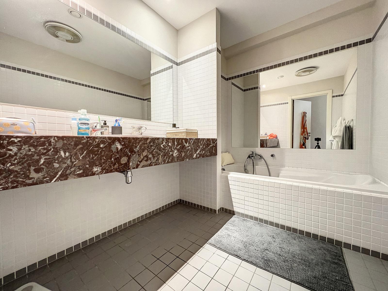 Salle de Bain Lumineuse avec Baignoire – You Real Estate Agency Salle de bain moderne lumineuse avec baignoire encastrée, grands miroirs et vasque en marbre