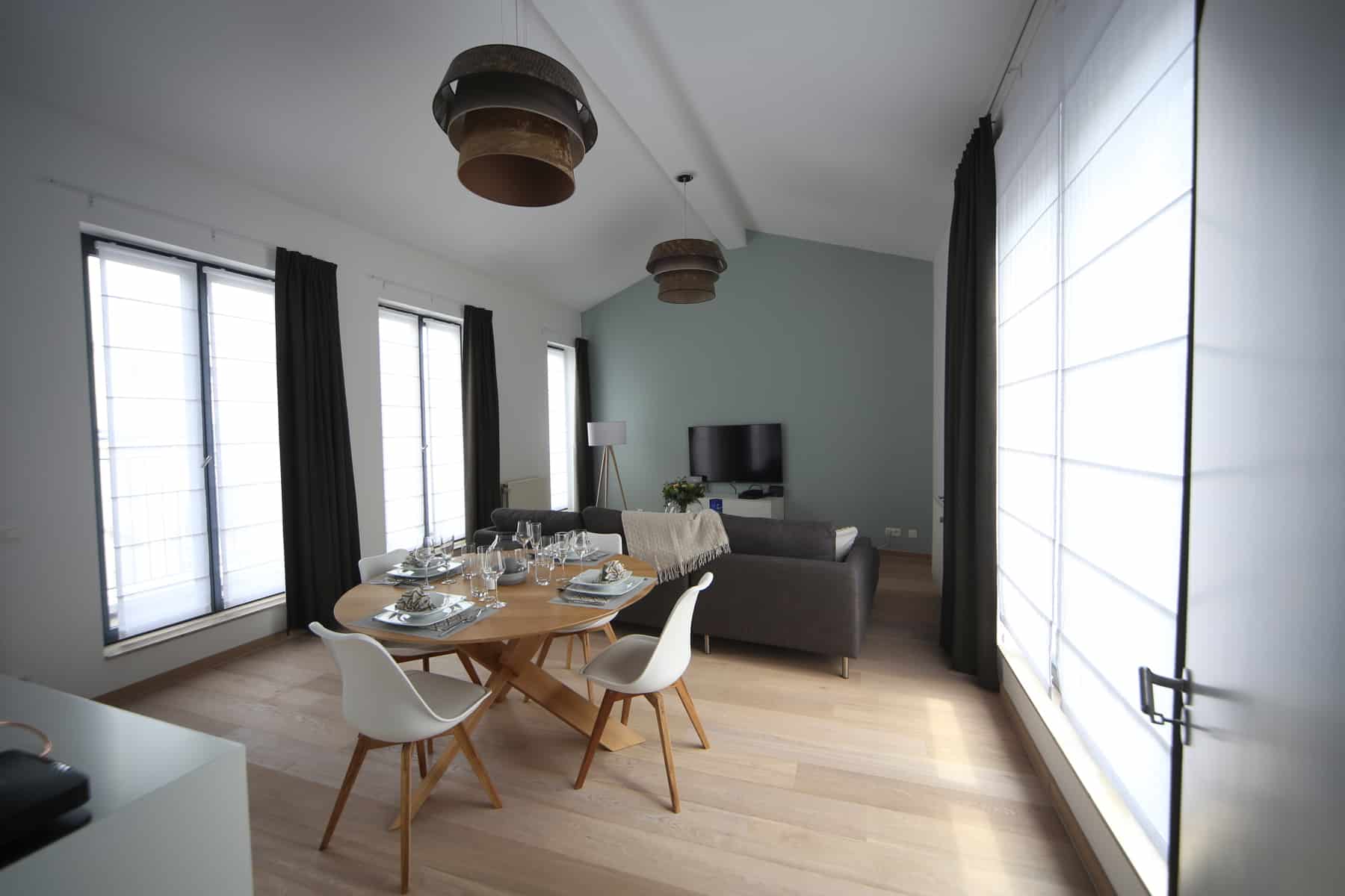 Séjour Ouvert avec Table Dressée – You Real Estate Agency Séjour ouvert lumineux avec salle à manger, table dressée et canapé gris