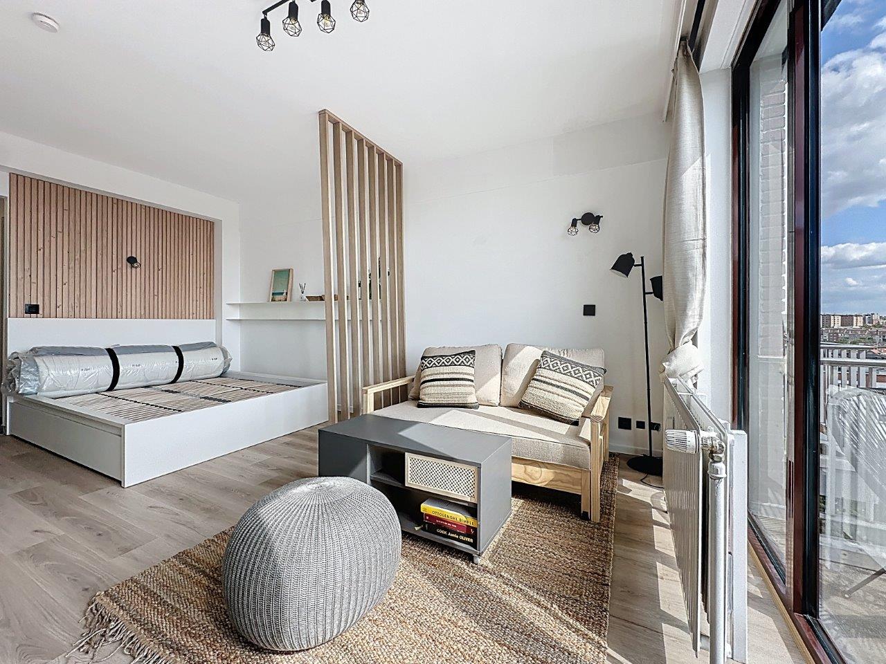Studio Lumineux avec Vue Urbaine – You Real Estate Agency Studio scandinave lumineux avec coin nuit, salon et grandes baies vitrées vue urbaine.
