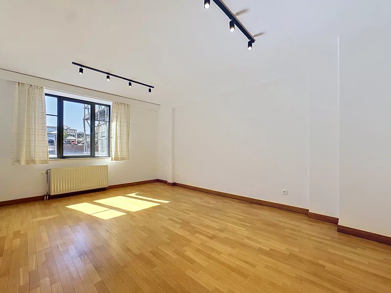 Bright living room with parquet floor - You Real Estate Agency Bright living room in empty apartment with parquet floor, large window and white walls.