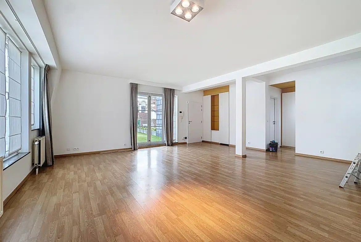 Grand salon lumineux d’appartement avec parquet, baies vitrées et accès jardin.