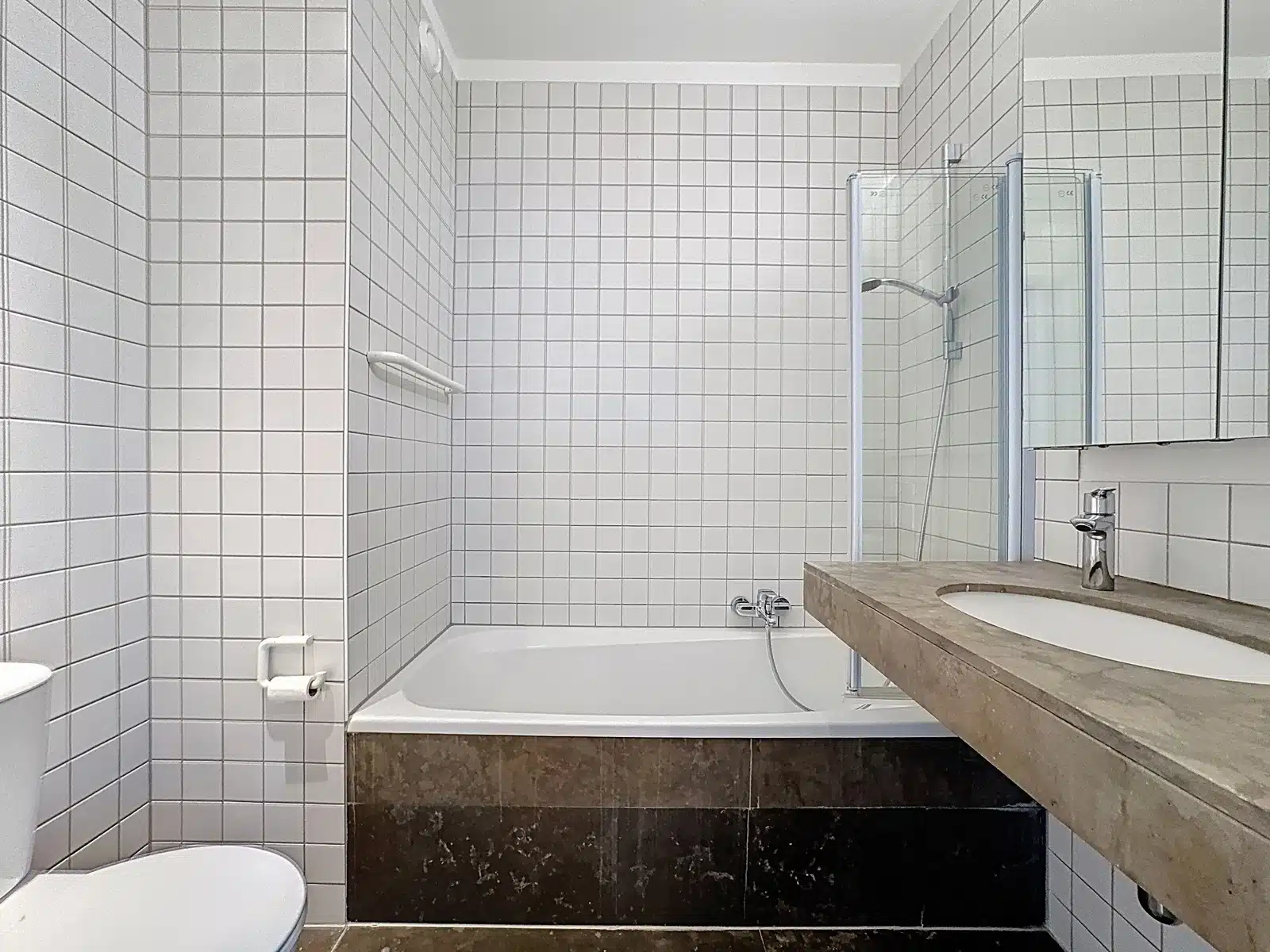 Salle de Bains Moderne – You Real Estate Agency Salle de bains moderne avec baignoire, douche vitrée et vasque en appartement.
