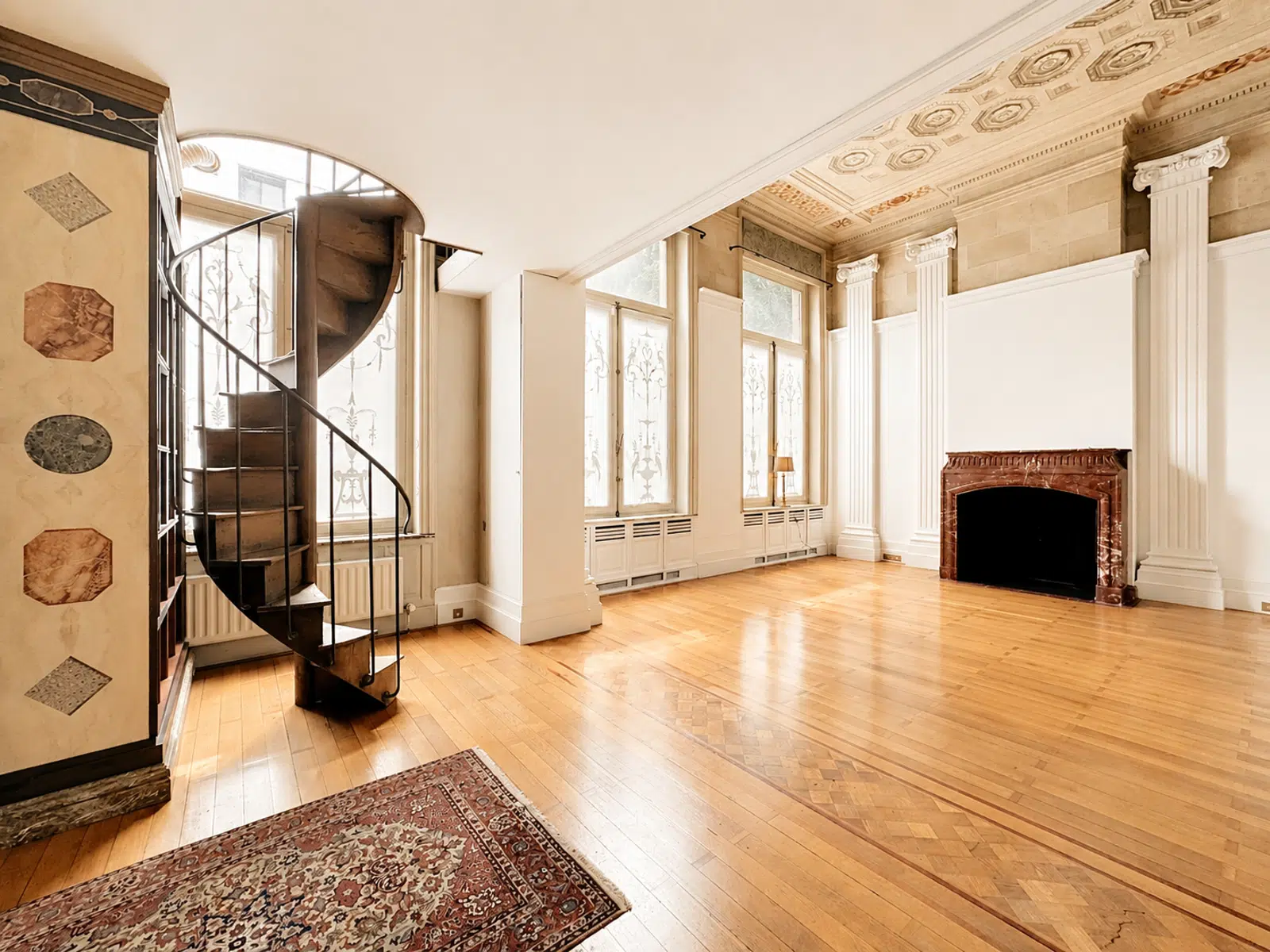 whise photo 3 Elegant historic living room with a black spiral staircase, tall frosted windows, decorative ceiling, and a marble fireplace.