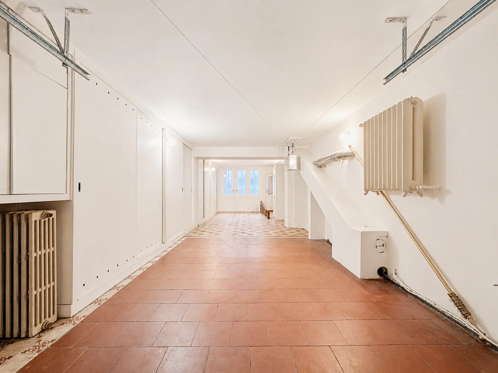Grenier Aménagé Lumineux – You Real Estate Agency Grenier aménagé lumineux avec rangements intégrés et portes vitrées dans appartement rénové.