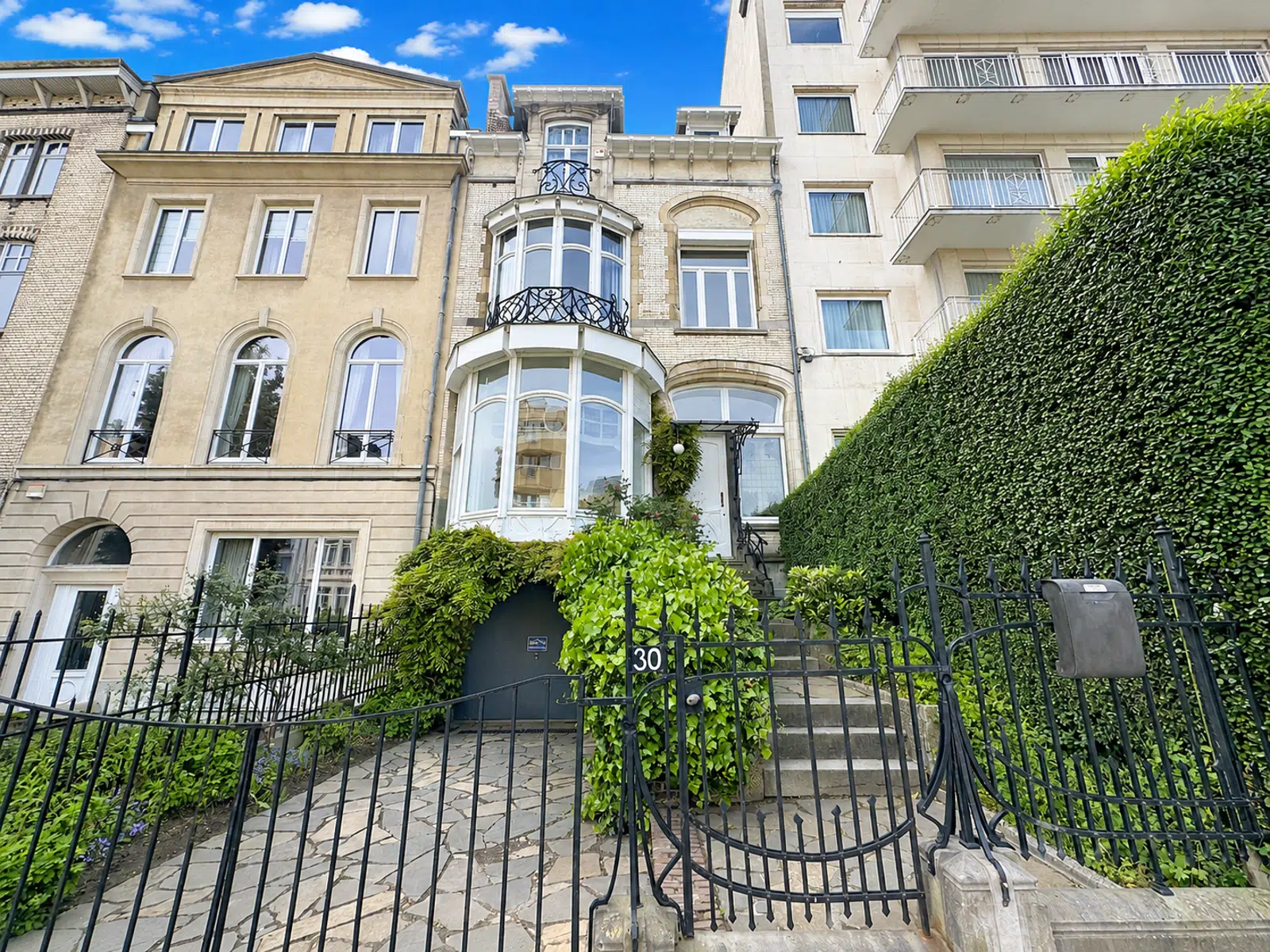 Maison de Maître avec Façade Élégante – You Real Estate Agency Maison de maître avec façade élégante, balcon en fer forgé et jardin urbain.