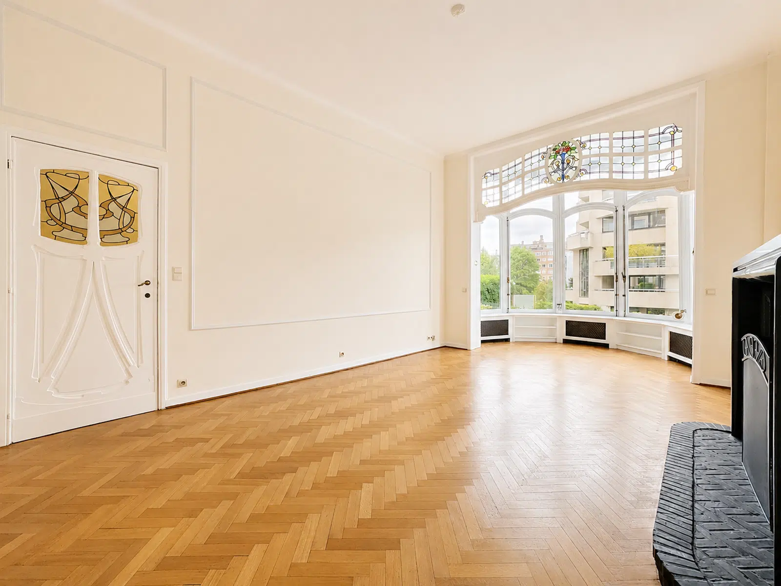 Salon Ancien Lumineux avec Vitraux – You Real Estate Agency Salon lumineux d’appartement ancien avec parquet, vitraux et baie vitrée.