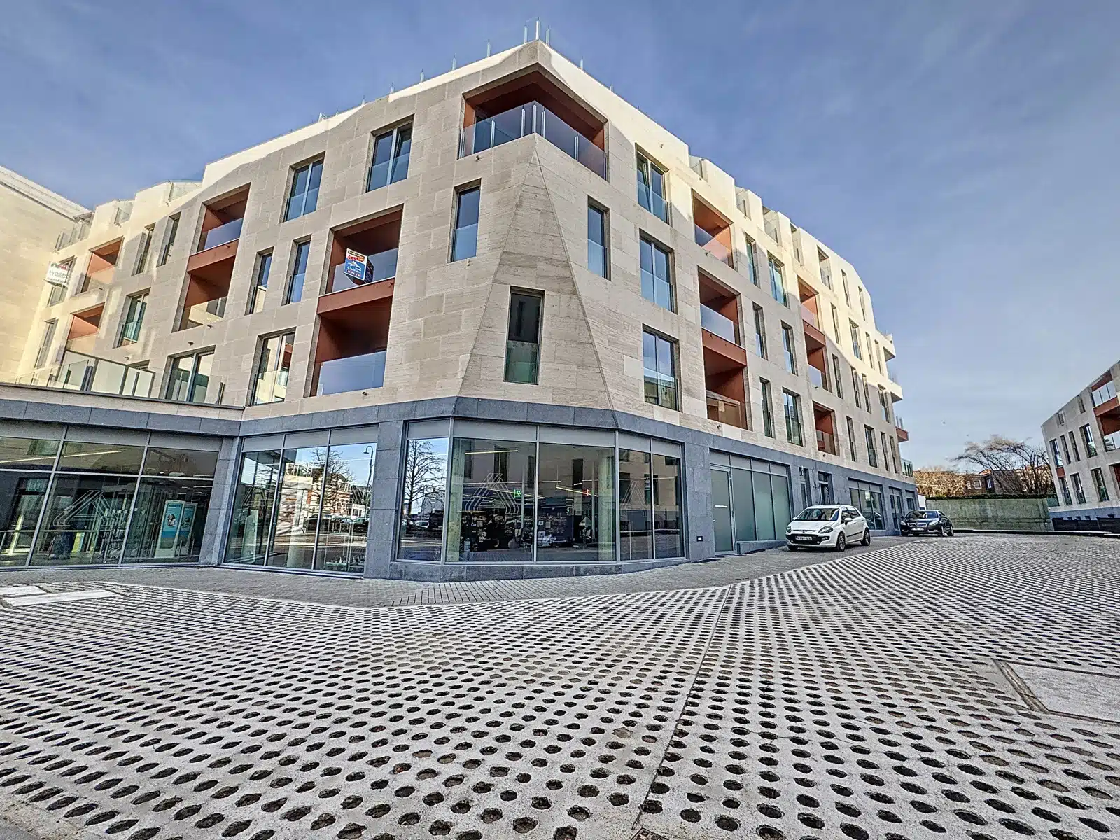 Moderne gevel met balkons - Uw Makelaarskantoor Modern woongebouw met appartementen, glazen terrassen en stenen gevel.