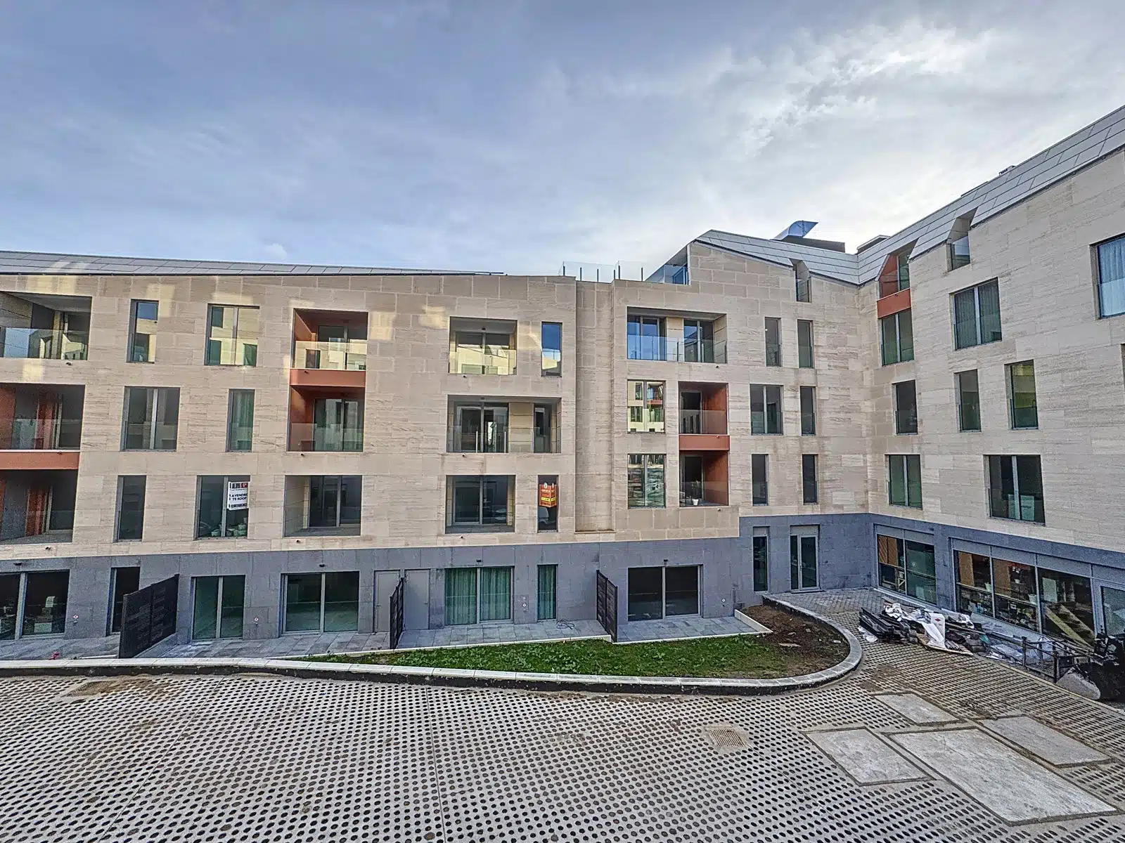 Moderne gevel met binnenplaats - You Real Estate Agency Een nieuwe residentie met appartementen, glazen balkons en een eigentijdse binnenplaats.