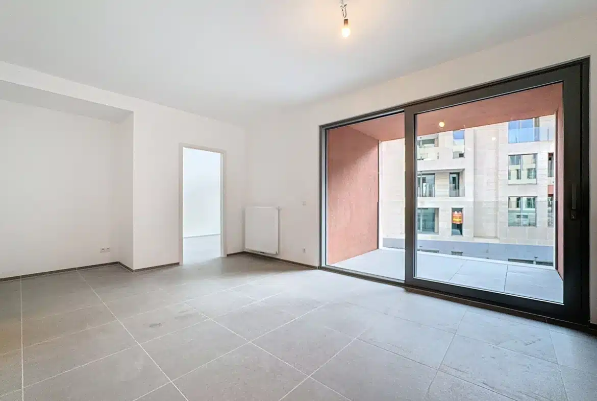 Salon lumineux d’appartement moderne avec grandes baies vitrées et terrasse.