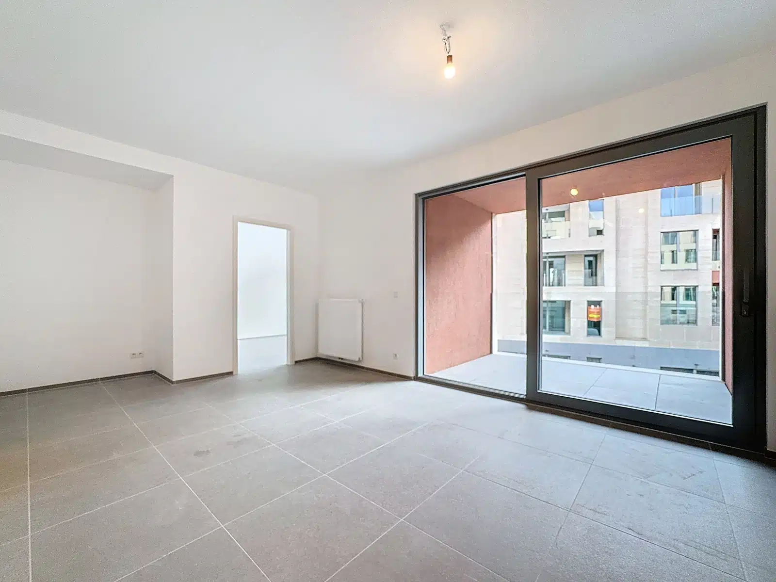 Lichte woonkamer met terras - You Real Estate Agency Lichte woonkamer in een moderne flat met grote ramen en terras.