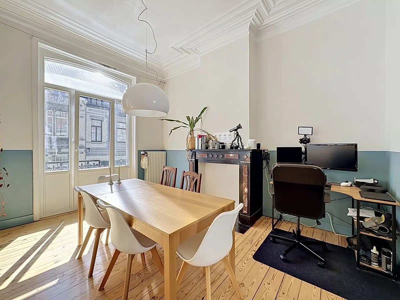 foto 4 Lichte kamer voor meerdere doeleinden met een houten eettafel en witte stoelen, bij een groot raam dat zonlicht binnenlaat.