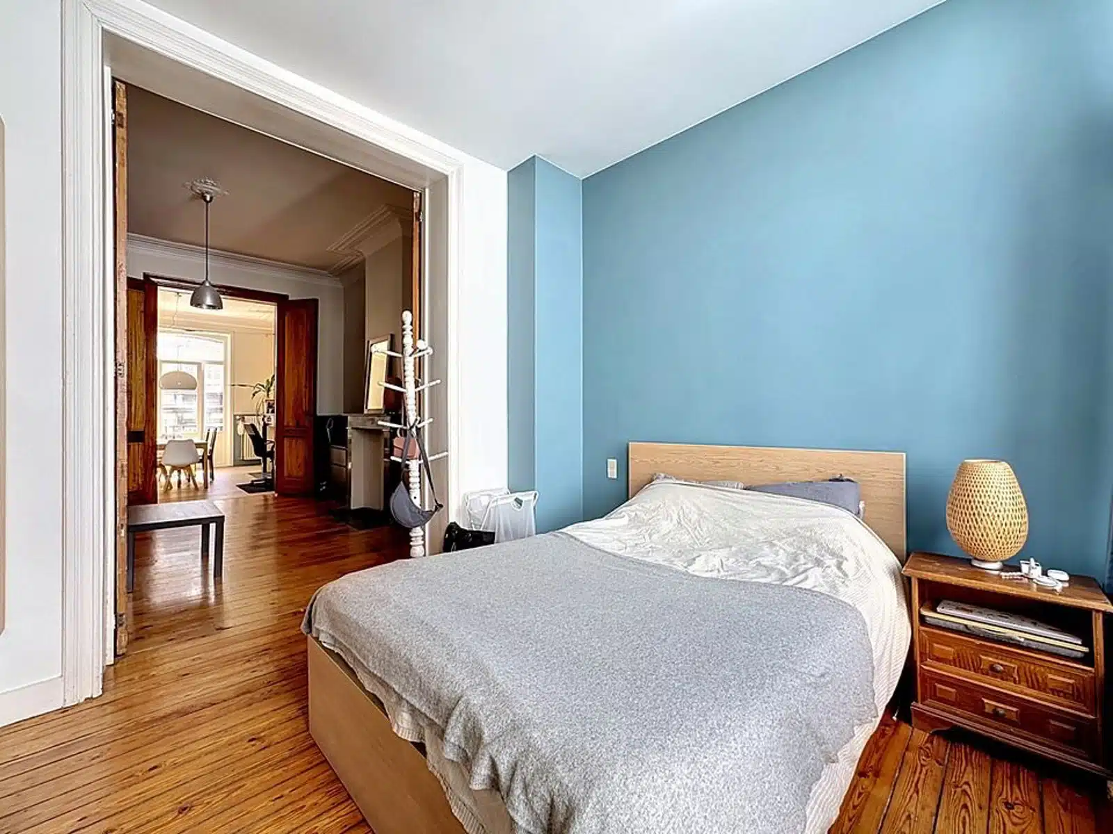 wijs foto 12 Slaapkamer met blauwe accentmuur, houten vloer en een laag houten bed; nachtkastje met geweven lamp vlakbij.