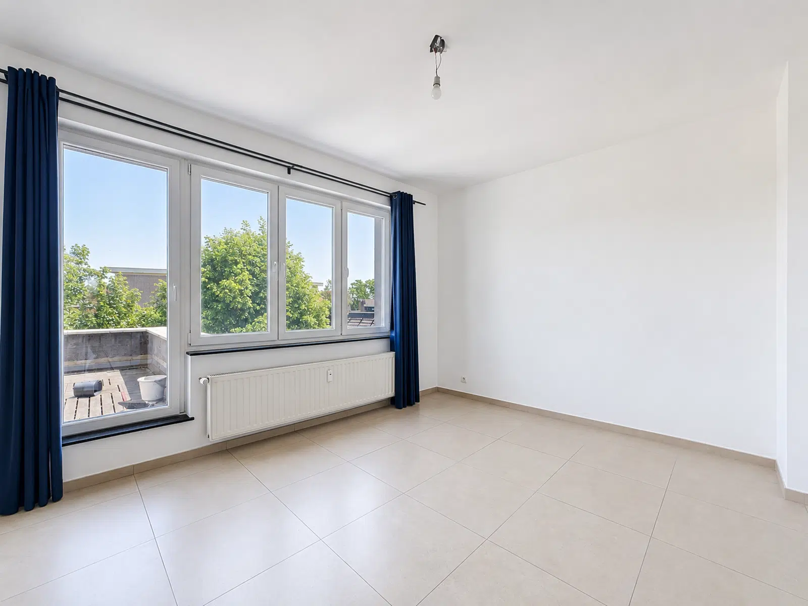 Pièce Lumineuse avec Terrasse – You Real Estate Agency Pièce lumineuse d’appartement avec grandes fenêtres, terrasse et carrelage clair.