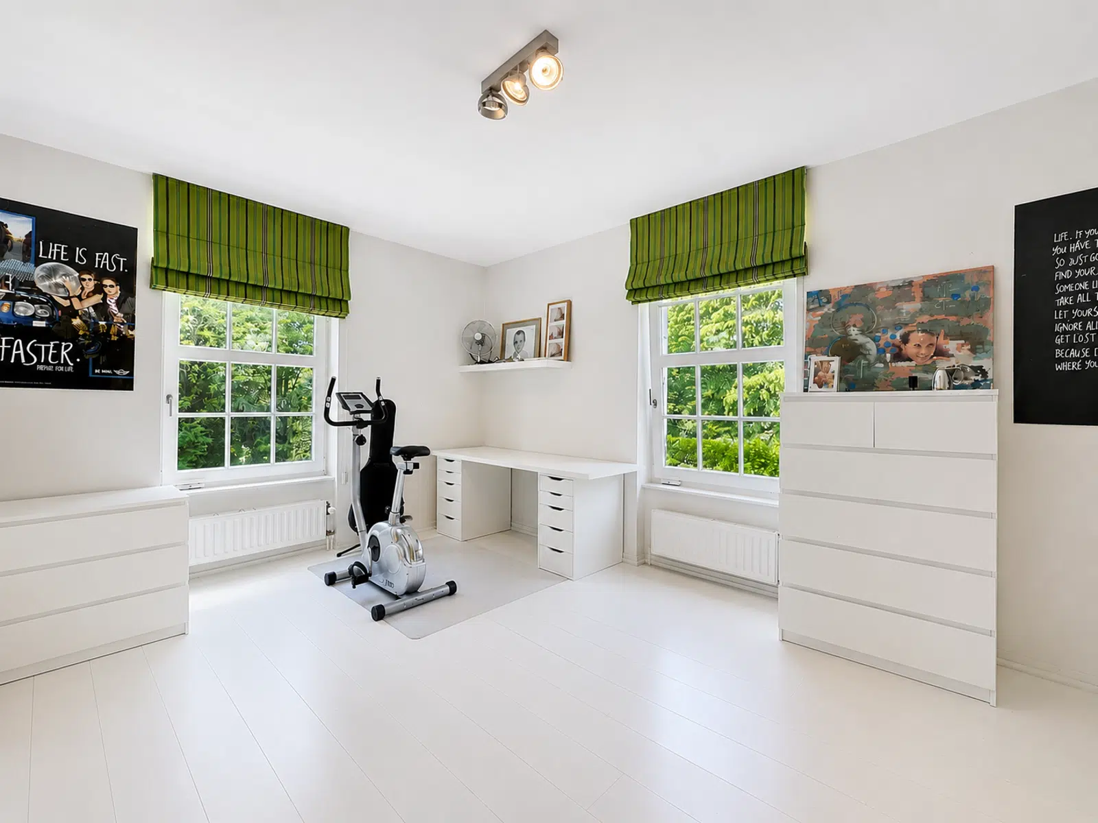 Bureau Lumineux avec Coin Sport – You Real Estate Agency Bureau lumineux avec coin sport, rangements blancs et grandes fenêtres dans maison moderne.