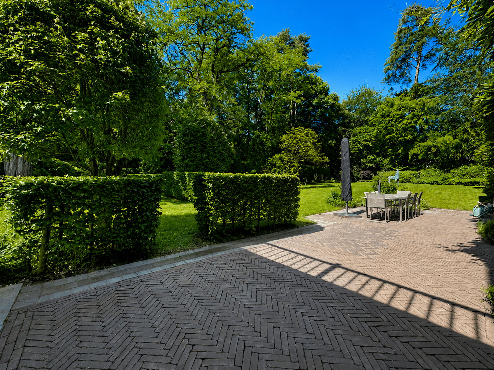 Terrasse Avec Jardin Paysager – You Real Estate Agency Terrasse en briques avec jardin paysager et mobilier extérieur de maison.