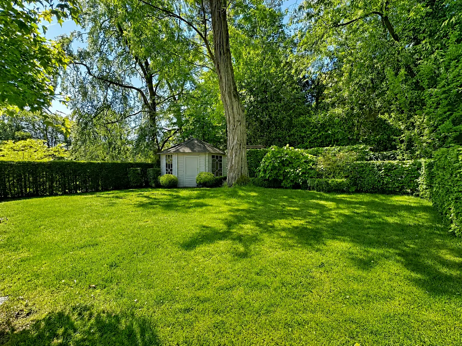Jardin Paysager Avec Abri – You Real Estate Agency Jardin arboré avec pelouse et abri de jardin pour maison.