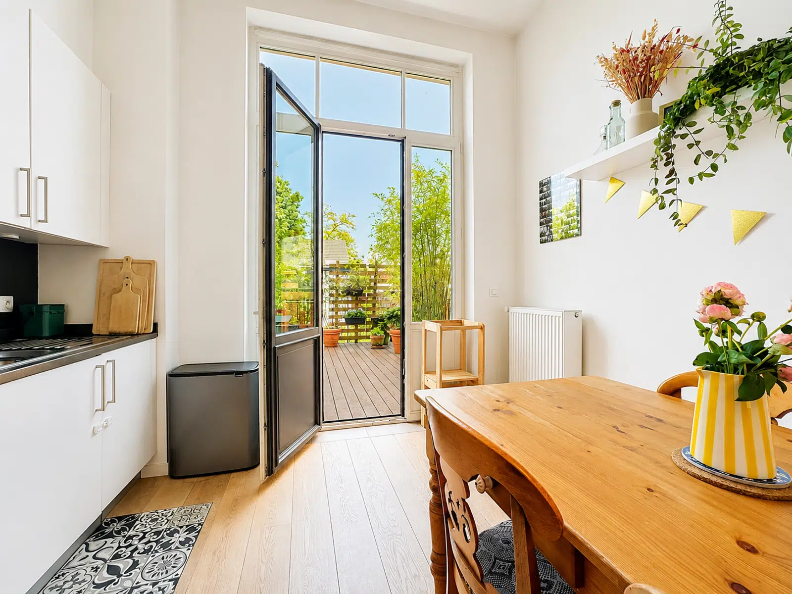 Cuisine Lumineuse avec Terrasse – You Real Estate Agency Cuisine lumineuse avec coin repas et terrasse végétalisée dans un appartement moderne.