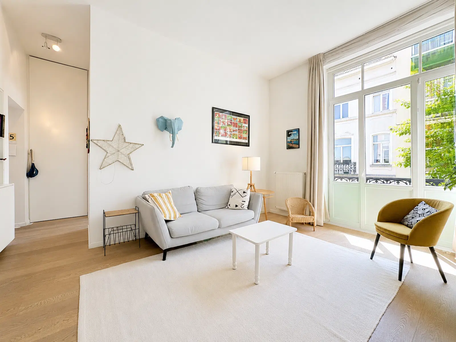 Salon Lumineux avec Hauts Plafonds – You Real Estate Agency Salon lumineux d’appartement avec hauts plafonds, parquet clair et grandes fenêtres.