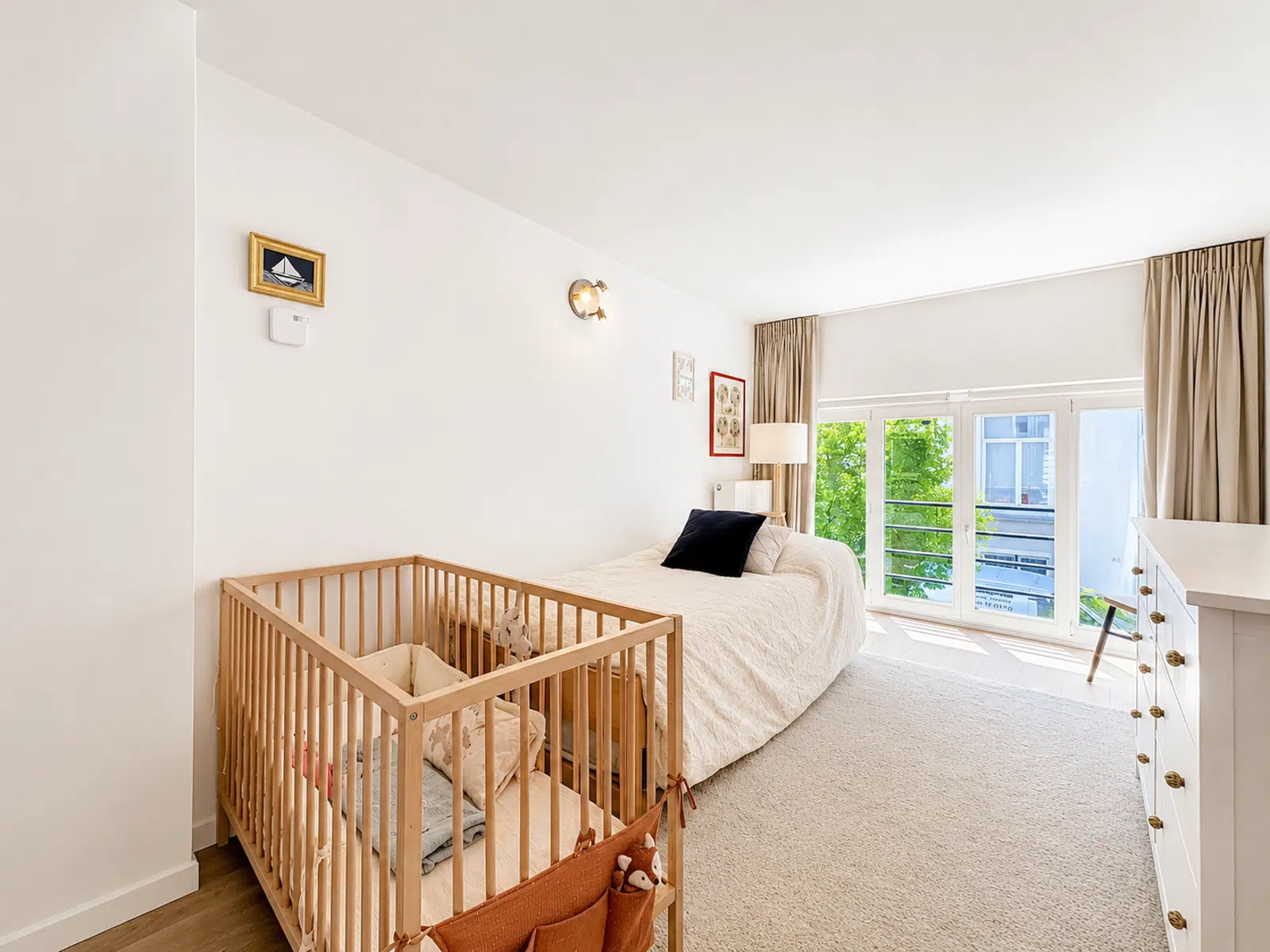 Chambre Bébé Lumineuse avec Balcon – You Real Estate Agency Chambre lumineuse avec lit, berceau et balcon dans un appartement familial.