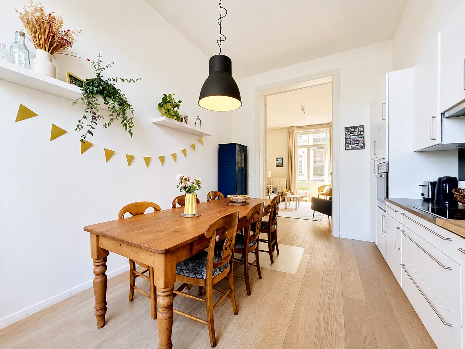 Salle à Manger et Cuisine Ouverte – You Real Estate Agency Salle à manger lumineuse avec cuisine moderne ouverte et parquet en bois.