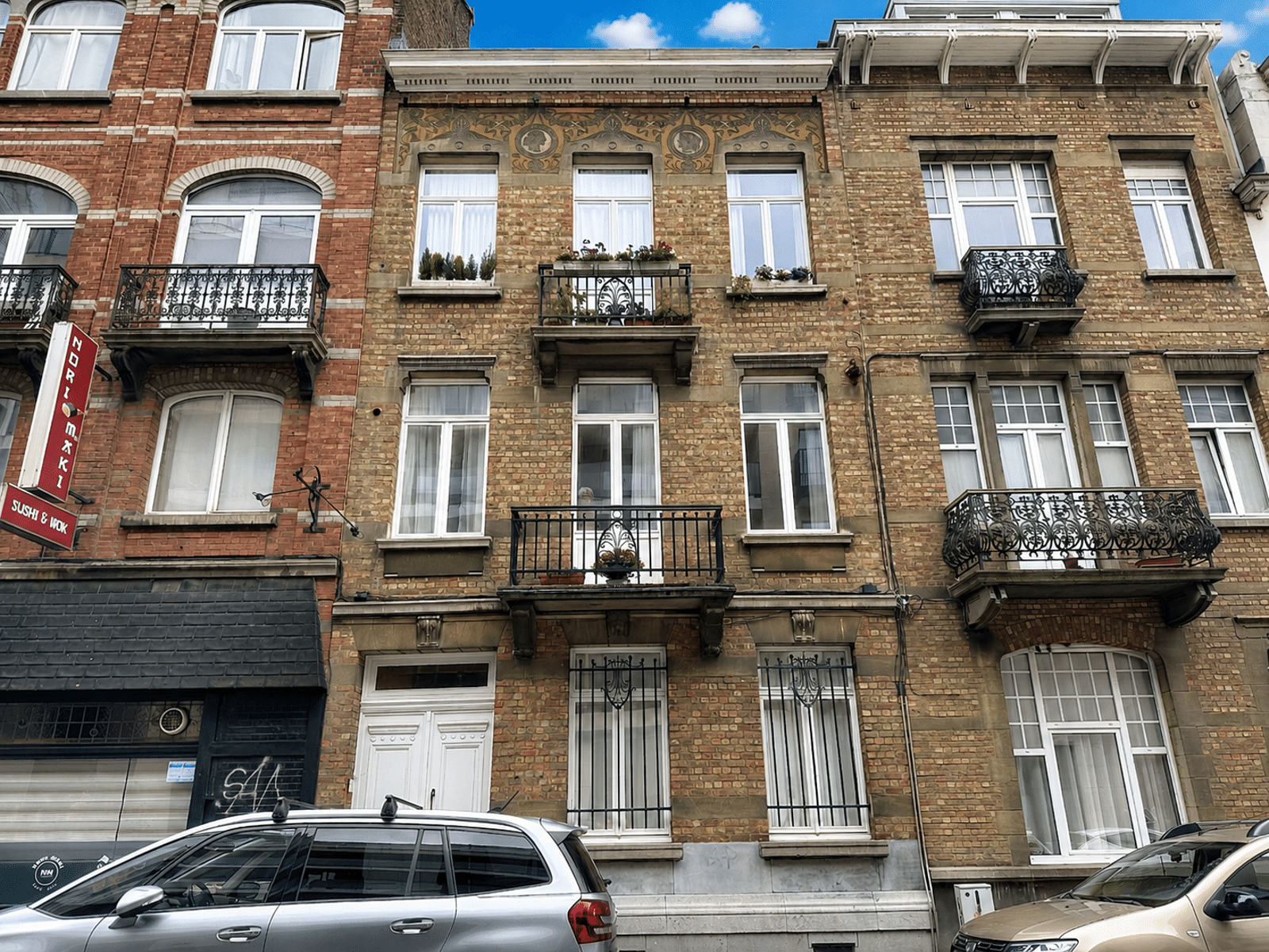 Façade en Brique avec Balcons – You Real Estate Agency Façade d’immeuble en brique avec balcons en fer forgé et commerces