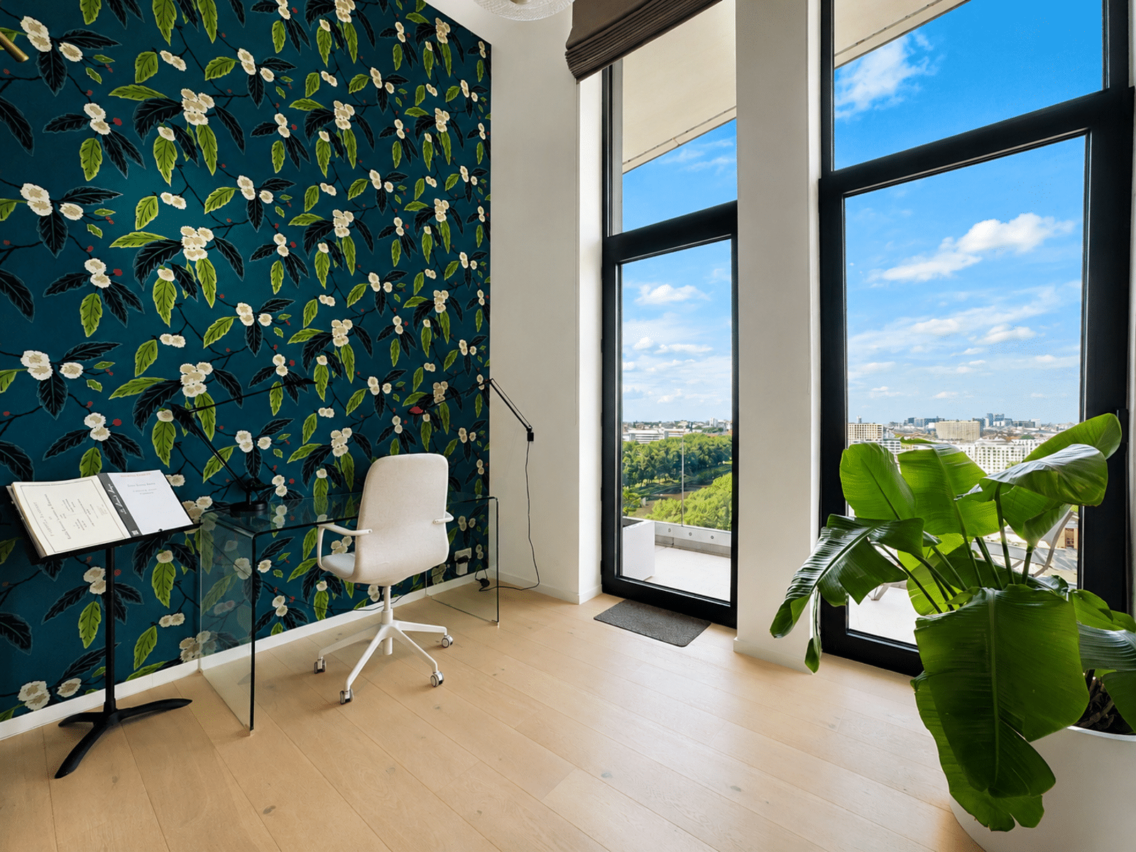 Bureau Lumineux au Papier Peint Floral – You Real Estate Agency Bureau lumineux d’appartement avec papier peint floral et terrasse vue ville.
