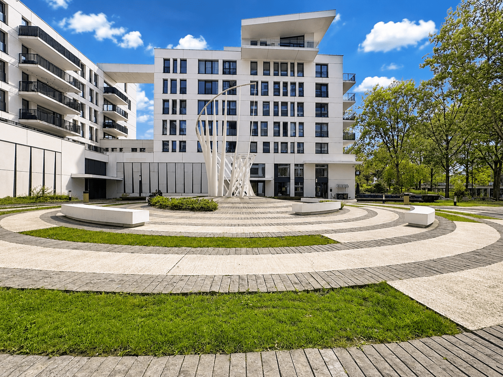 Cour Intérieure Moderne Paysagée – You Real Estate Agency Cour intérieure moderne avec appartements, terrasses, sculpture et espaces verts paysagers.