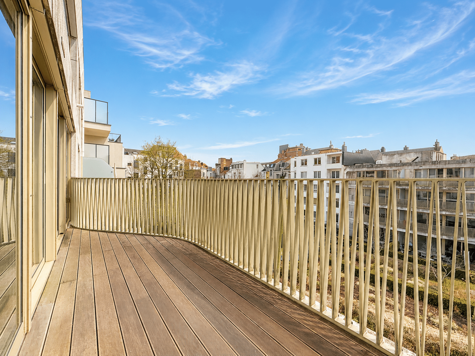 Terrasse en Bois avec Vue Urbaine – You Real Estate Agency Grande terrasse en bois d’un appartement moderne avec vue urbaine dégagée.