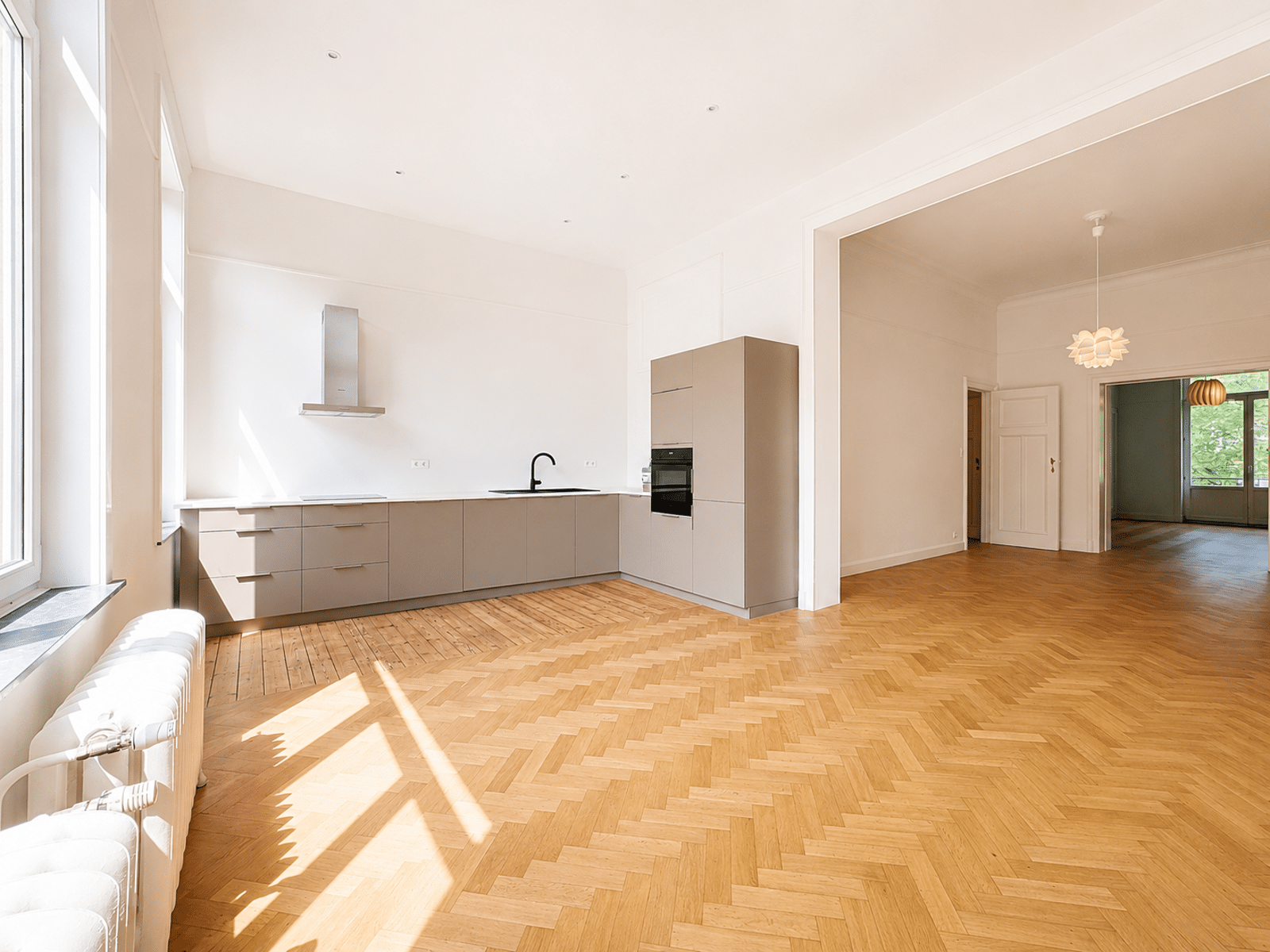 Cuisine Ouverte Lumineuse avec Parquet – You Real Estate Agency Cuisine ouverte moderne et salon lumineux avec parquet en chevrons dans appartement rénové.