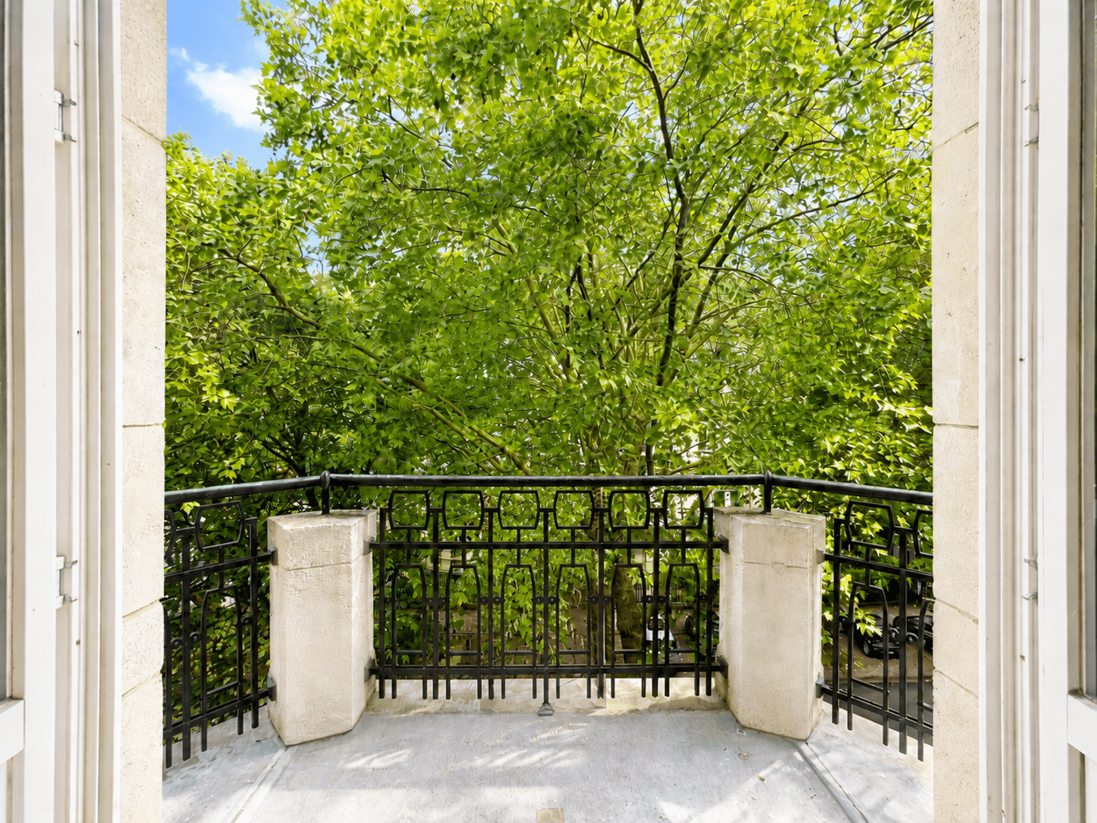 Balcon Lumineux Avec Vue Arborée – You Real Estate Agency Balcon lumineux d’appartement avec garde-corps en fer forgé et vue arborée.