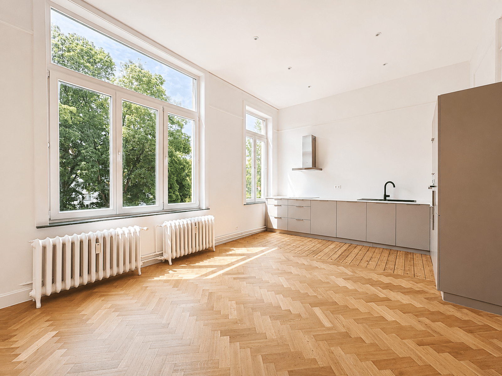 whise photo 4 Bright, minimalist kitchen with large windows, white walls, gray cabinets, and a herringbone wood floor.
