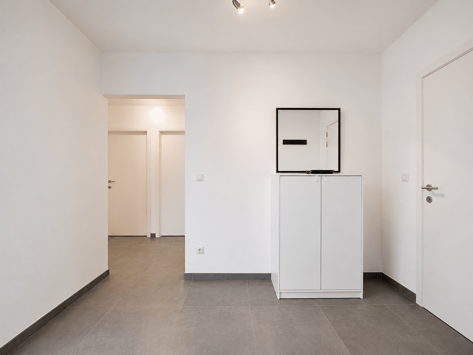 Modern Apartment Entrance Hall - You Real Estate Agency Modern apartment entrance hall with gray tiles, white furniture and mirror.